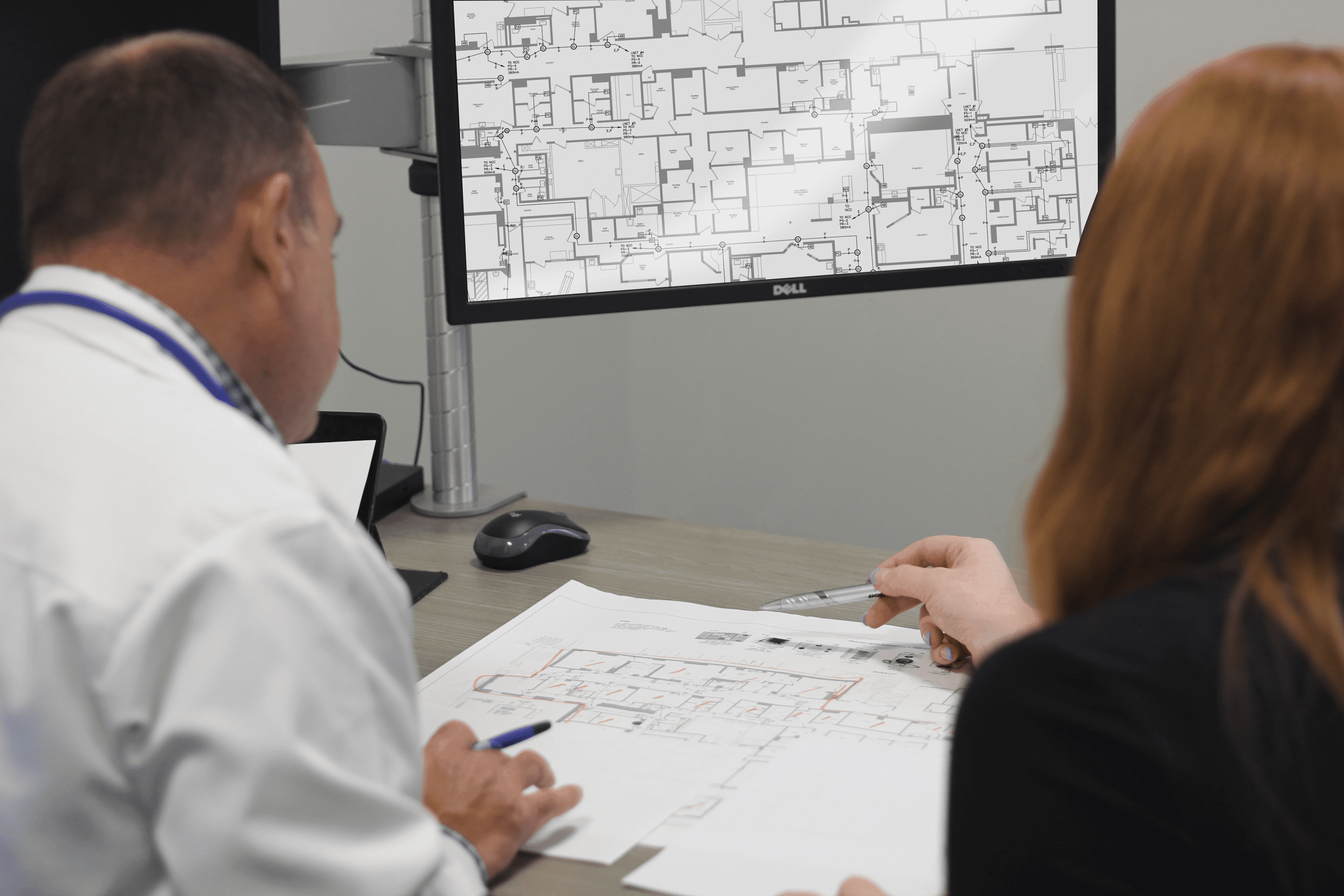 “Male and Female employees collaborating and reviewing blueprint plans for a project”